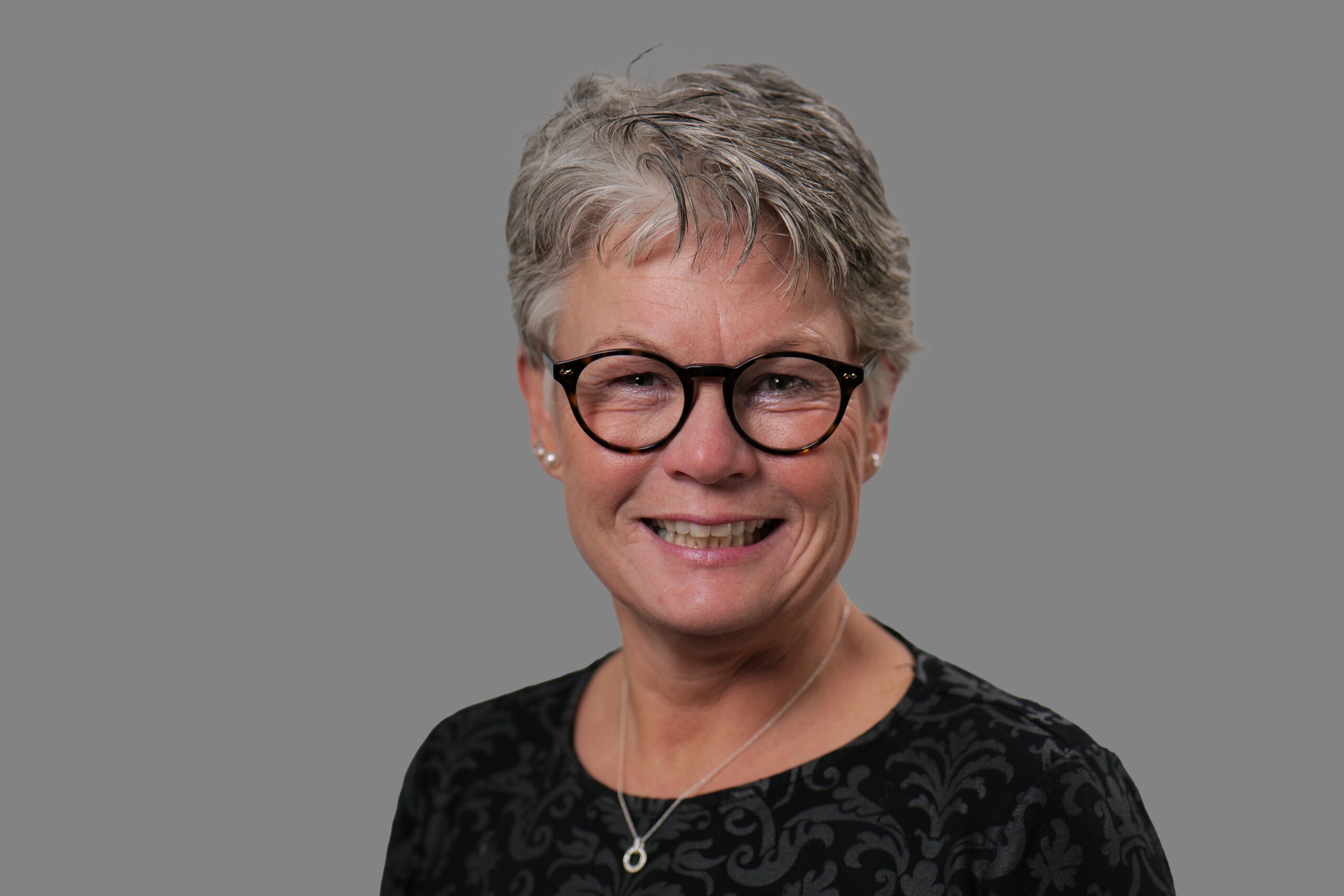 Kari Fretheimin muotokuva. Hänellä on tumma villapaita, mustat silmälasit ja tummanharmaat lyhyet hiukset. Hän hymyilee.