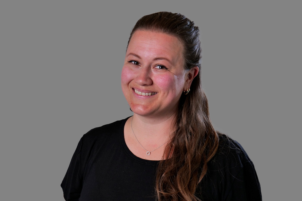 Ragnhild Bjørgum har langt mørkt hår i en hestahale hengende ned over skulder. Hun smiler med åpen munn. Har på en sort t-skjorte.