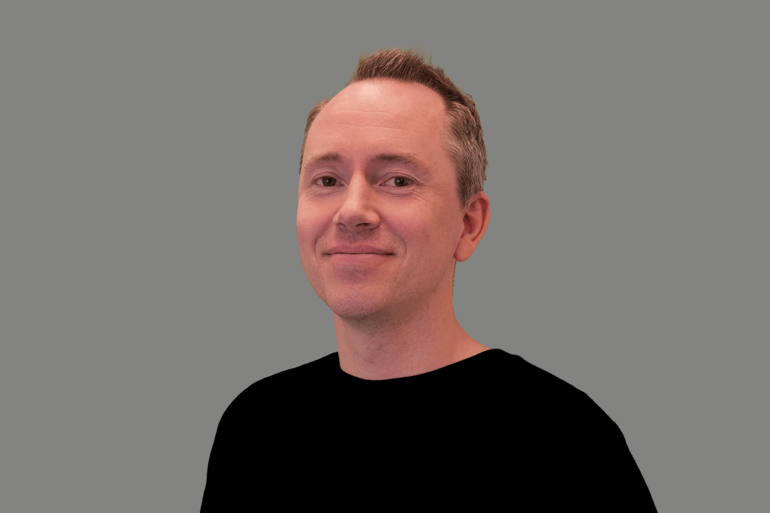 Thomas har kort brunt hår, litt grått på siden. han har på en sort t-skjorte.