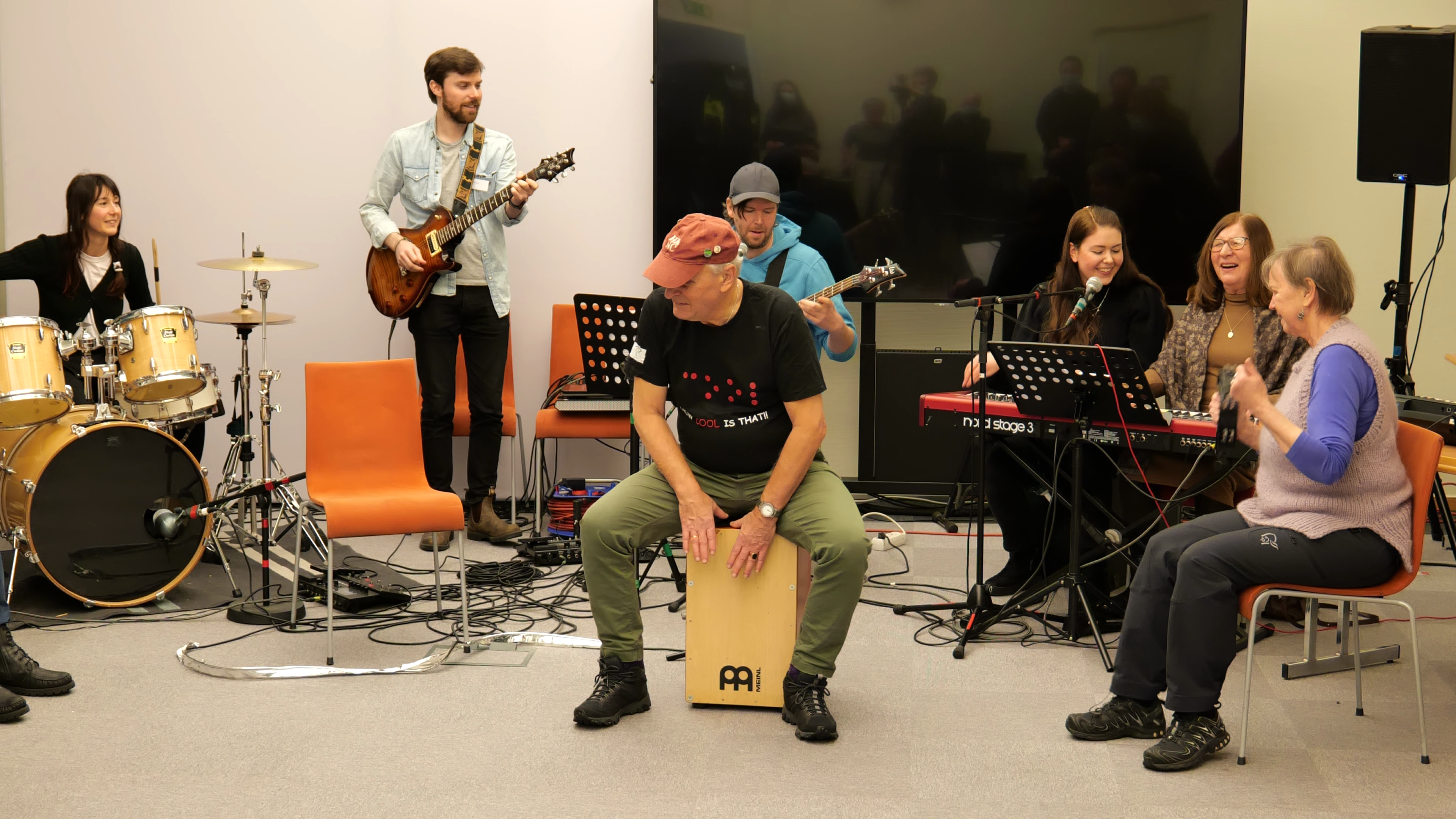 Et band med flere musikere, i front en person som spiller en håndtromme.