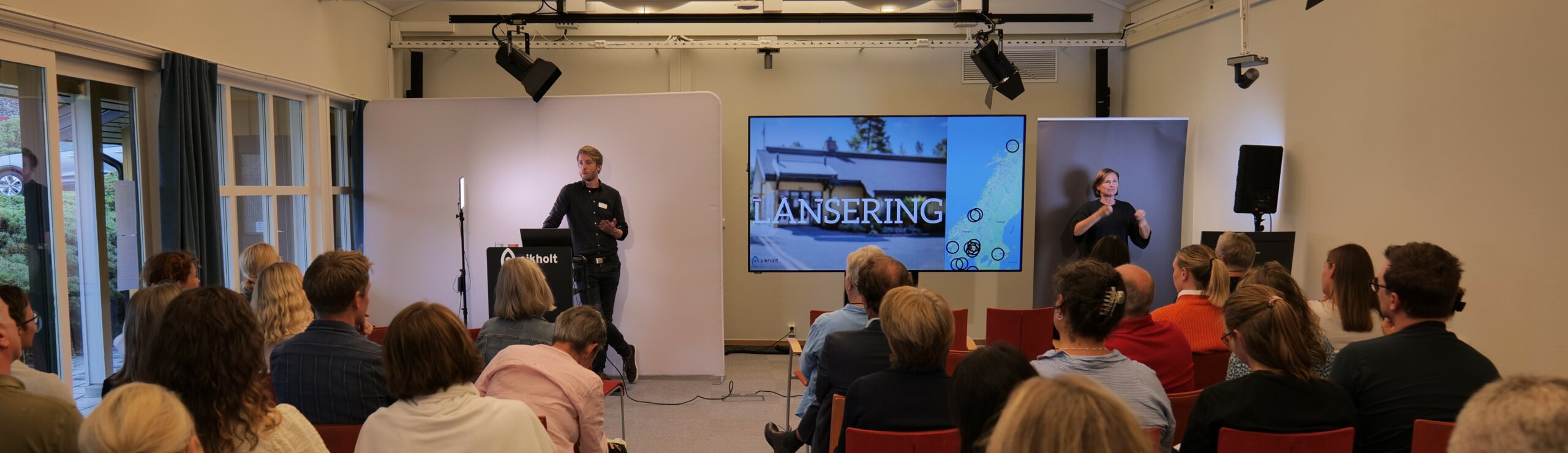 Rolf Mjønes står foran et publikum og presenterer Eikholt-testen på en skjerm