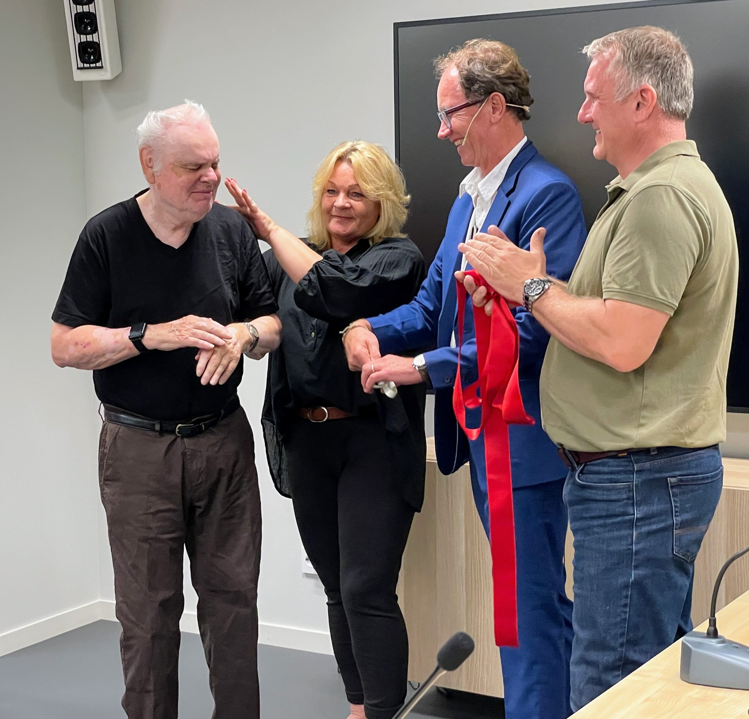 Harald Vik is standing with an interpreter, Director Roar Meland and Technical Manager Thomas Øverby. They are smiling and clapping.