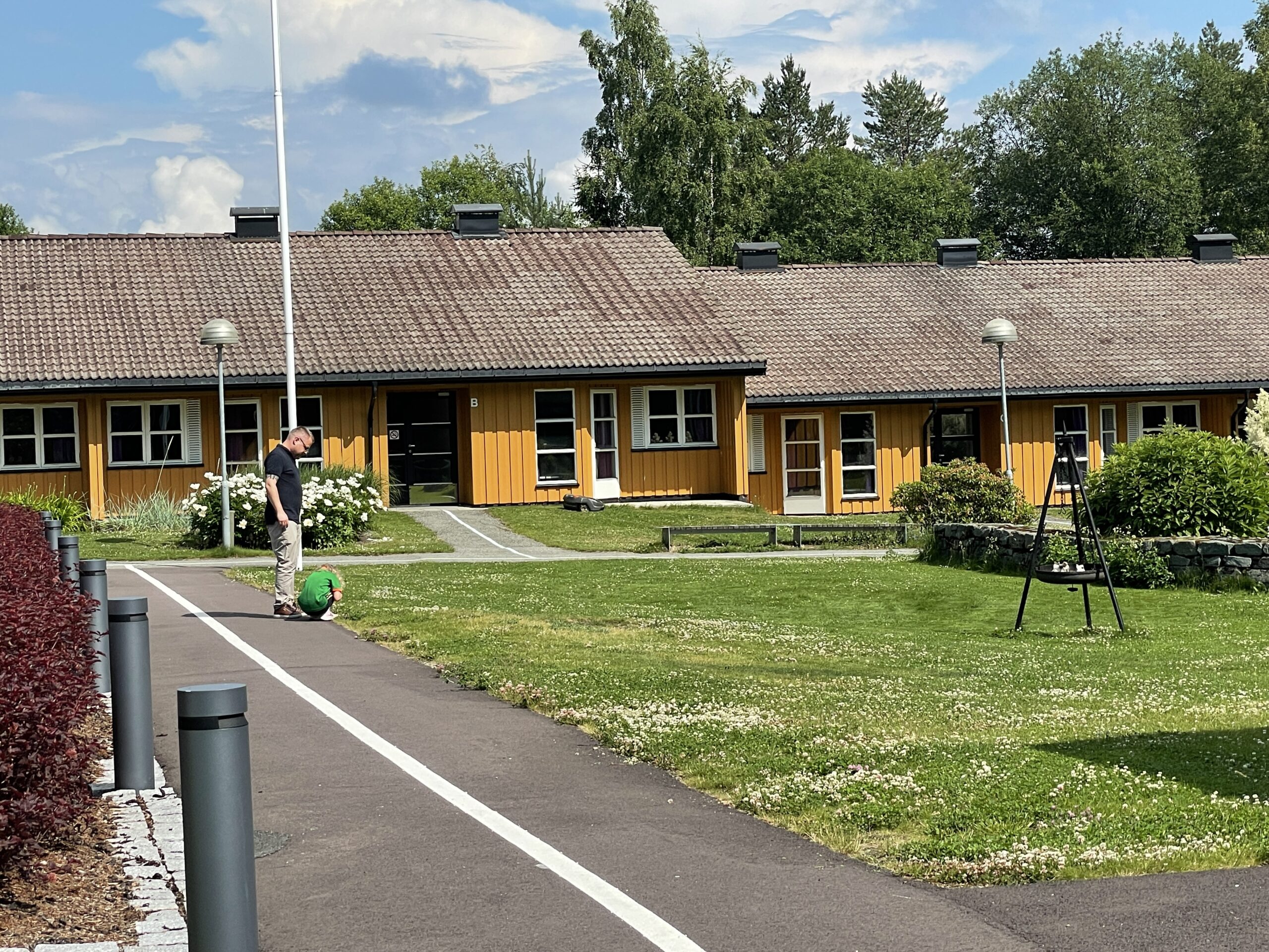 To personer vises langt borte på en gangsti med ledelinjer. I rundt vises bygninger og gress.