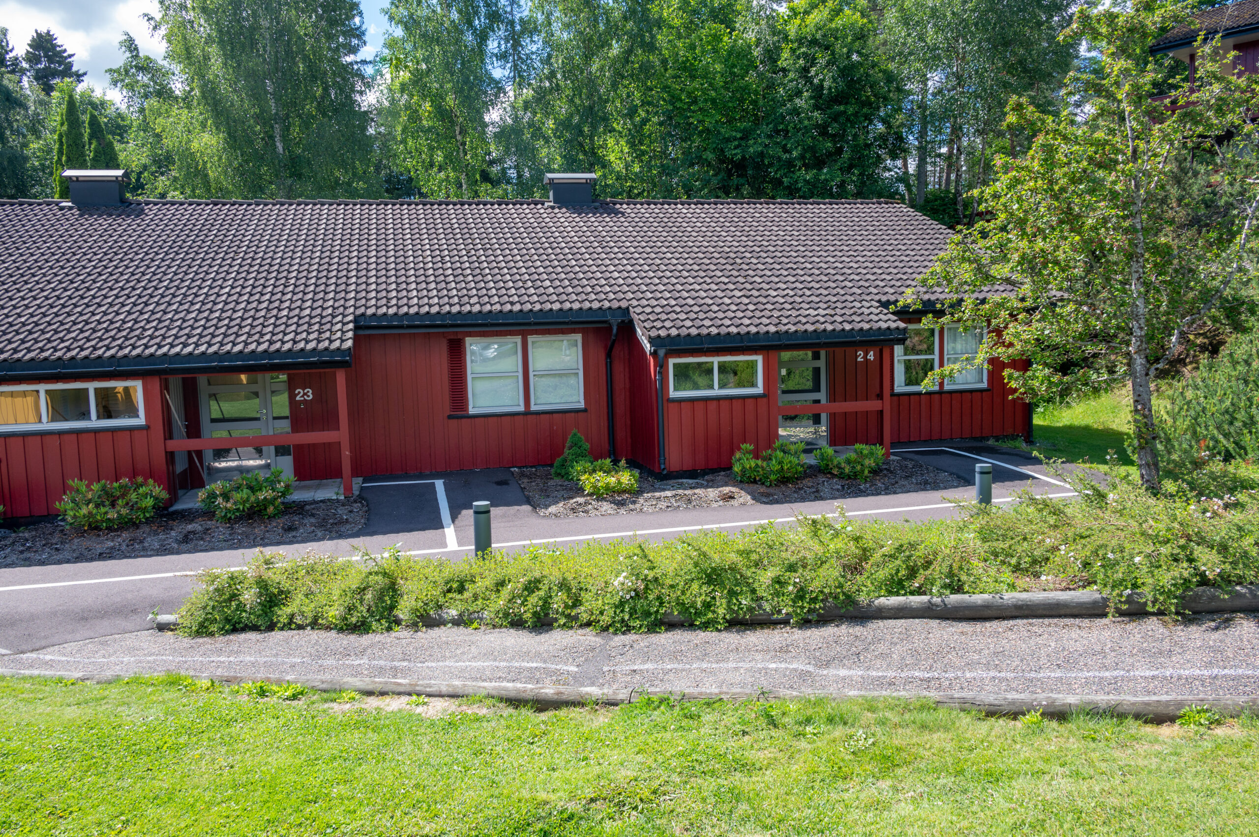 Matala pitkänomainen talo, kukkula, jonka edessä on nurmikkoa ja polkuja.