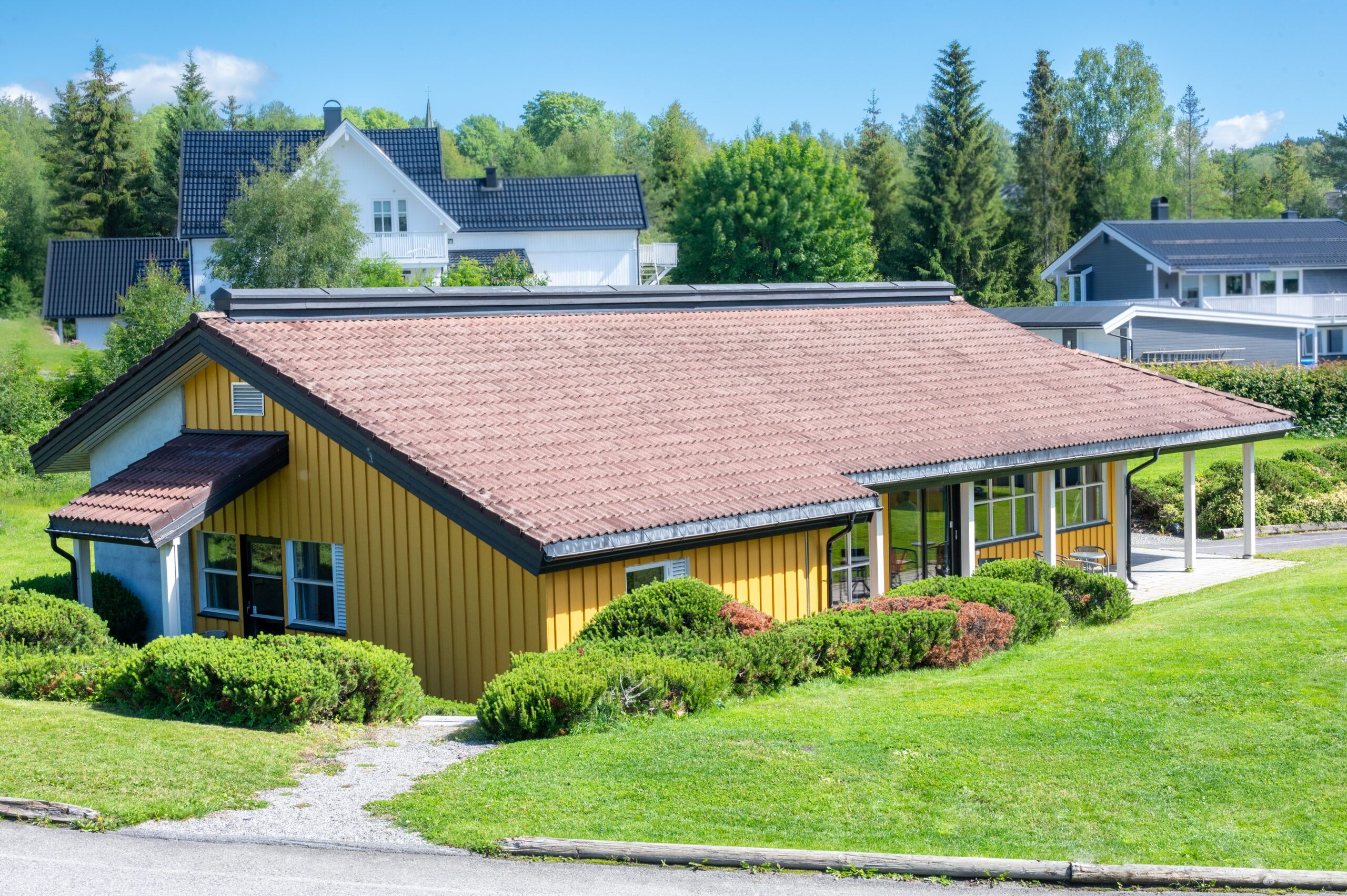 The Ragnhild Kaata building seen from the administration building. A low, oblong building with windows on the long side and grass outside.