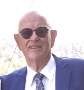 Portrait of Arne Kjeldstad. He has no hair and wears glasses. Wearing a suit, tie and white shirt.