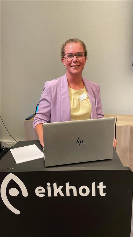 Emy Hurtig står bak en talerstol med en PC. Foran seg har hun en PC.