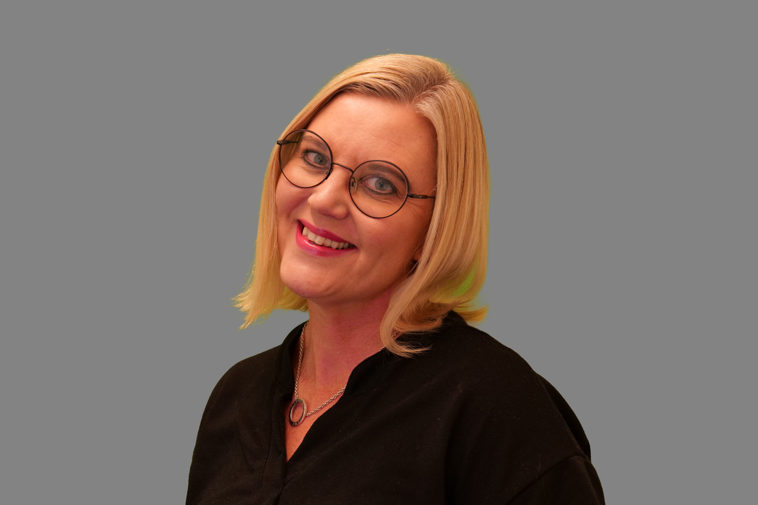 Portrett av Carolina Ahlèn. Hun har lyst hår ned til skuldrene, sideskrill og lang pannelugg. Hun bruker brille og har en sort bluse.