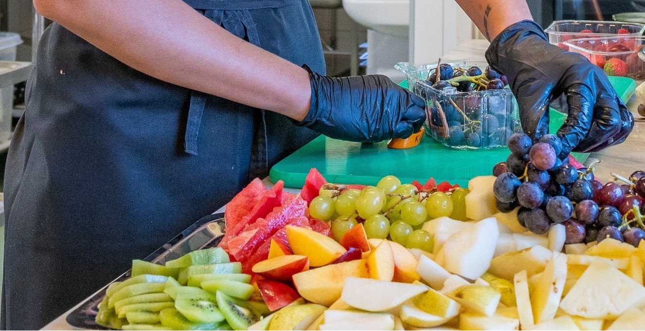 Hender som jobber med å skjære frukt som ligger på et skjærebrett