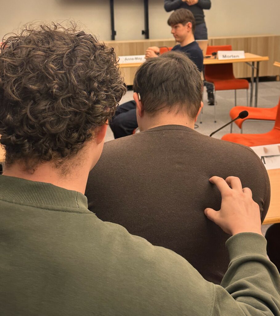 To personer i en forelæsning. Den ene laver haptiske signaler på den andens ryg