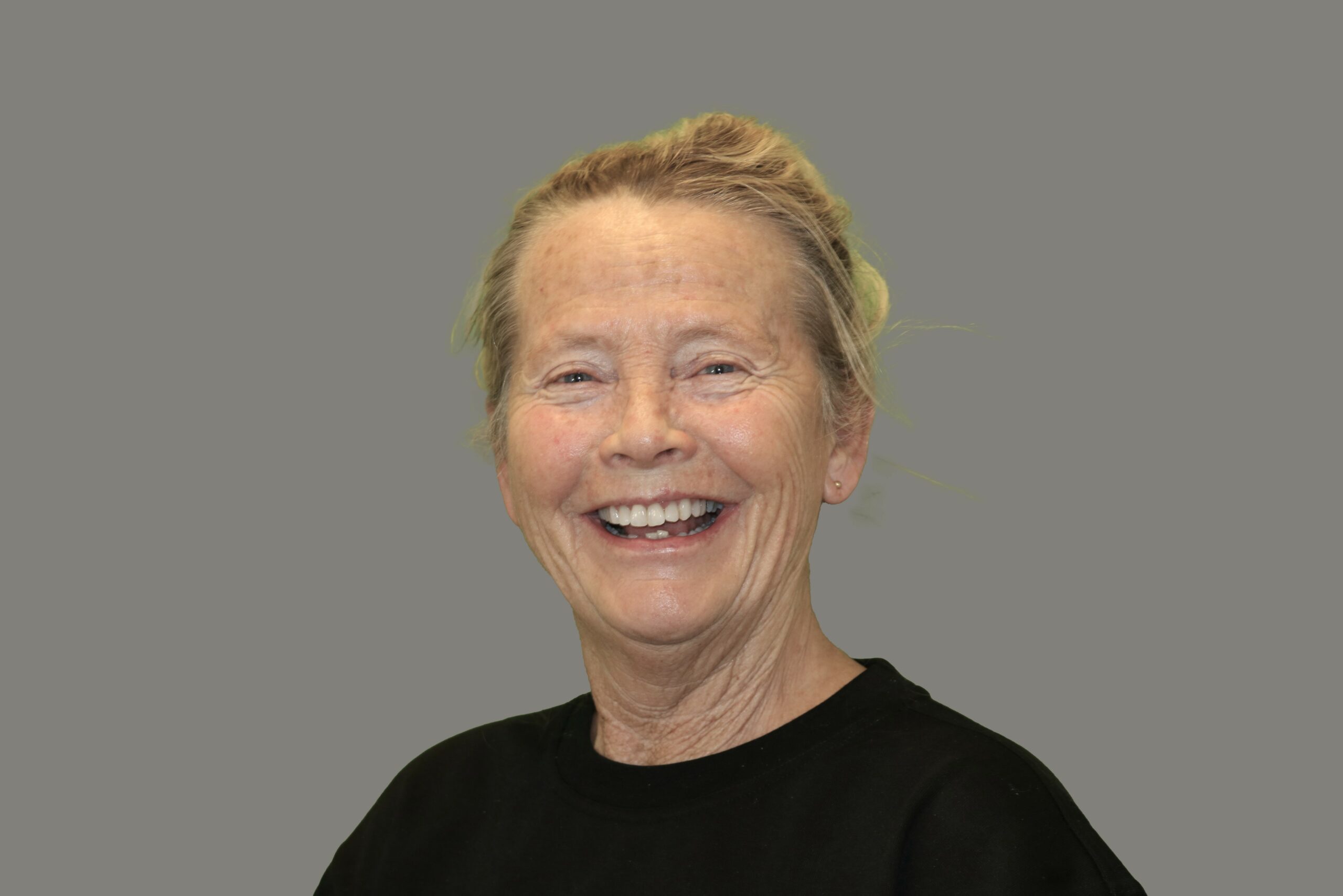 Jahne har grått hår som är något ljusare i topparna. Hon ler och är klädd i en svart t-shirt.