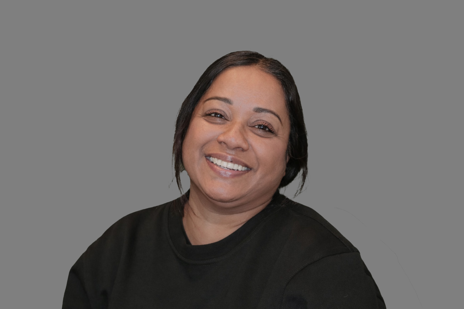 Portrett av Unn Asha. Hun har mørkt hår festet i en lav hestehale. Hun har mørke øyebryn og brune øyne. Hun smiler.